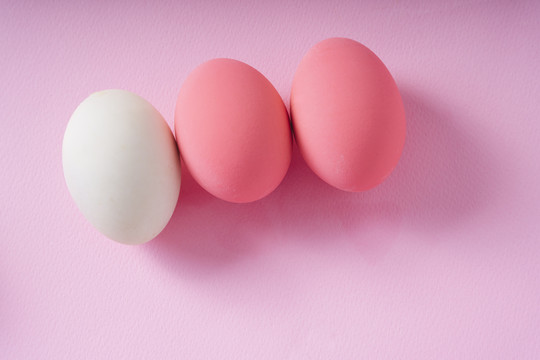 顶视图-粉红色背景上的一组白色和粉红色的鸡蛋。