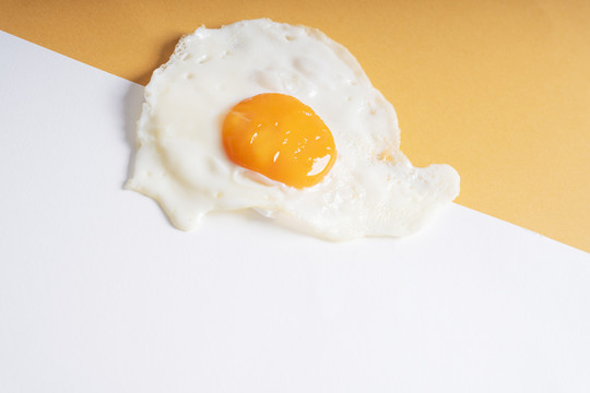 新鲜的煎鸡蛋在白色和黄色橙色的背景。