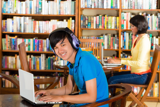 学生在图书馆写作，在笔记本电脑上学习一个年轻人的肖像