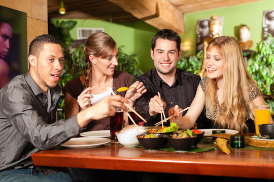 年轻人在泰国餐馆吃饭，他们用筷子吃饭