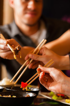 年轻人在泰国餐馆吃饭，他们用筷子吃饭