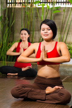 亚洲年轻女性坐在瑜伽的位置上，在热带环境下冥想