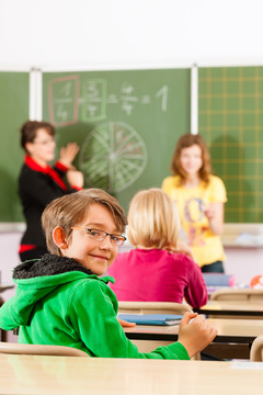 教育-年轻的女教师和学生在他的形式的小学或小学教学