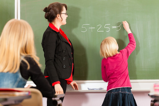 教育-年轻的女教师和学生在他的形式的小学或小学教学