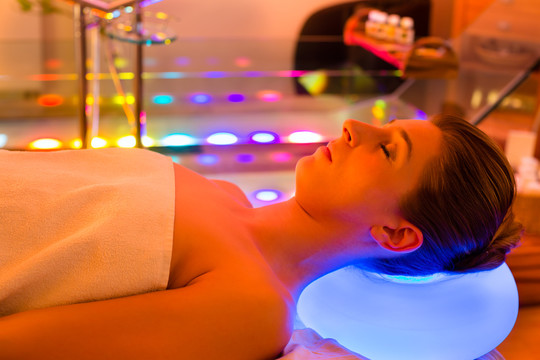 在水疗中心享受色彩疗法的女人，五彩缤纷的灯光刺激着心灵