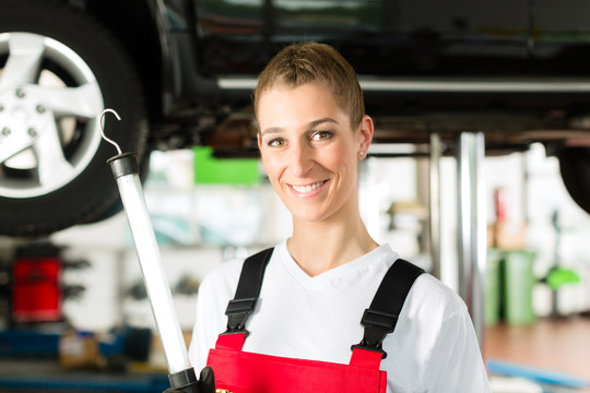 成熟的男性客户和年轻的女性汽车修理工在汽车引擎盖下寻找