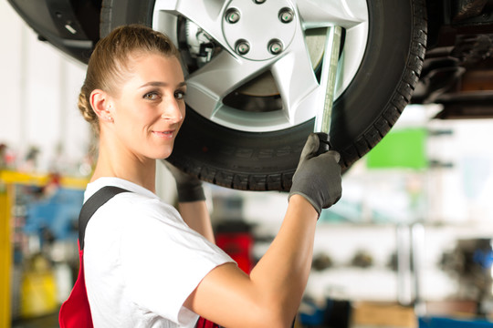 年轻女子作为女汽车修理工在工作站上工作
