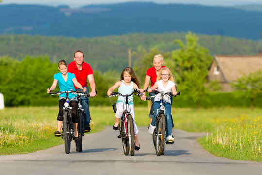 一家人带着三个女孩在美丽的风景中骑着自行车或是在夏天骑着自行车进行周末远足