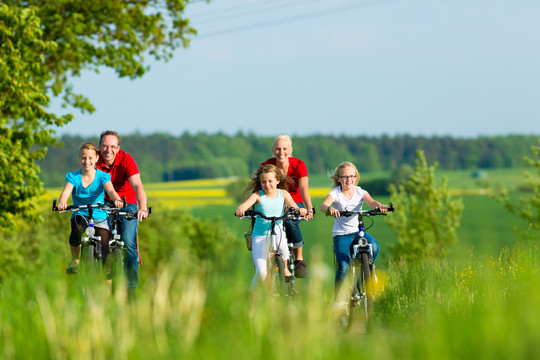 一家人带着三个女孩在美丽的风景中骑着自行车度过周末