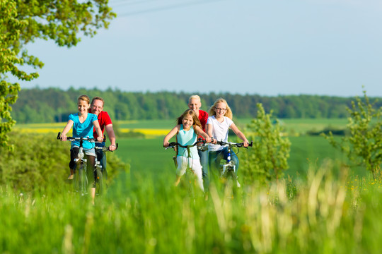 一家人带着三个女孩在美丽的风景中骑着自行车度过周末