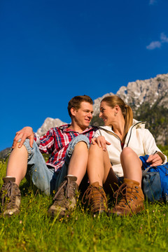 一对幸福的情侣在阿尔卑斯山的草地上散步，休息一下，欣赏山景