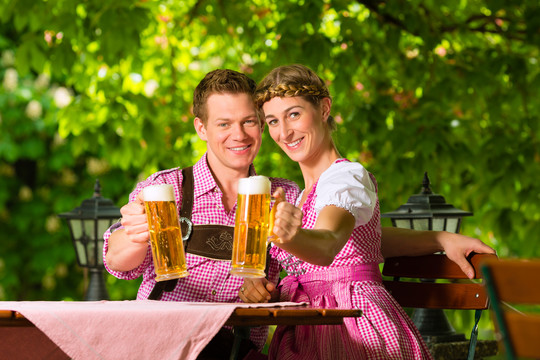 夏日里，幸福的一对坐在啤酒花园里，享受着一杯啤酒和阳光