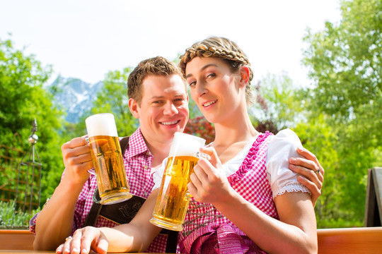 夏日里，幸福的一对坐在啤酒花园里，享受着一杯啤酒和阳光