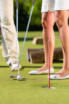 人们，男人和女人，只有脚，在美丽的夏日打迷你高尔夫