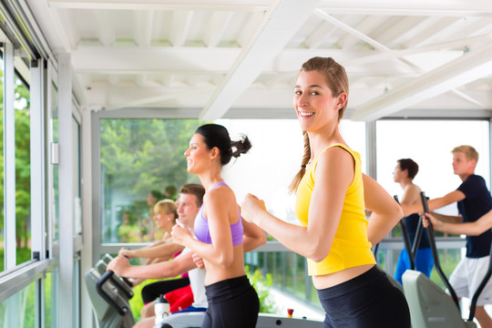 在健身房或健身俱乐部的跑步机上跑步-一组男女锻炼以获得更多的健康