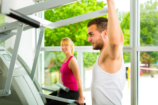 男人和女人在健身俱乐部或健身房的机器上训练