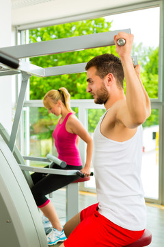男人和女人在健身俱乐部或健身房的机器上训练