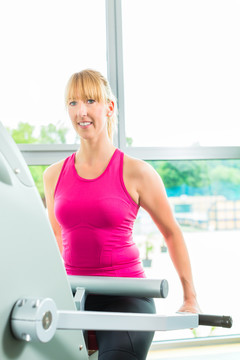 女子在健身房或健身俱乐部踏步锻炼，以获得更多的健身