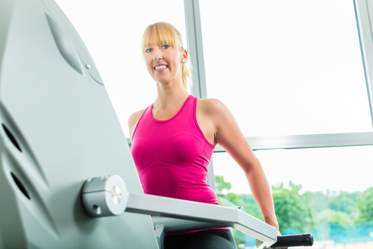 女子在健身房或健身俱乐部踏步锻炼，以获得更多的健身