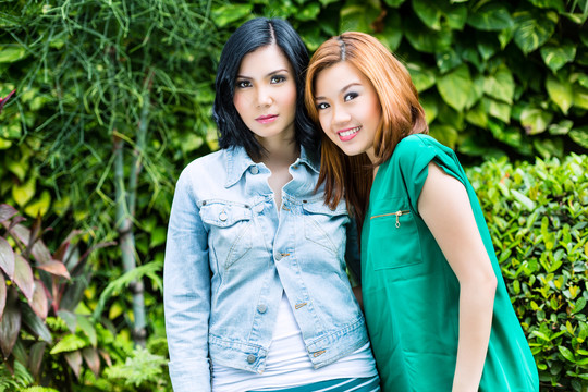 两个时髦的女朋友在绿茵场摆姿势，看着镜头