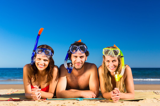 一群朋友-男人和女人-带着浮潜设备在沙滩上享受假期的乐趣