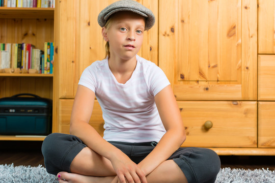 家庭-儿童或青少年戴着帽子坐在地板上的房间里