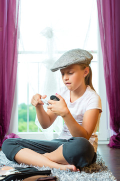 家庭-孩子或青少年戴着帽子坐在房间地板上化妆