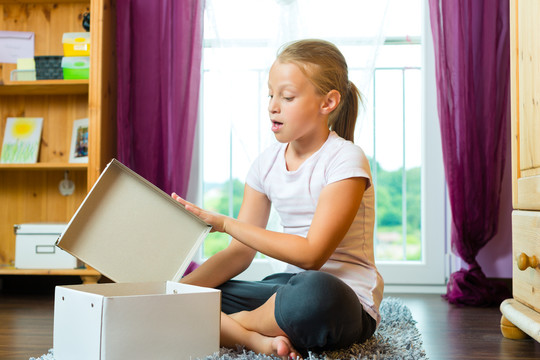 家庭-儿童或青少年在家中客厅打开礼物或盒子