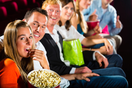 人们在电影院里看电影，在镜头前微笑，玩得很开心