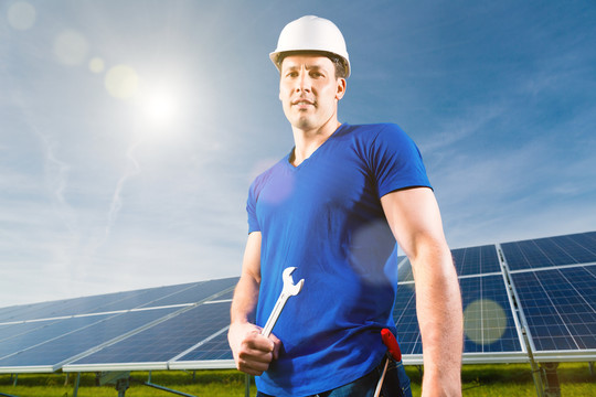 光伏发电系统用太阳能板生产可再生能源，通过太阳能，一名技术人员或工人站在前面