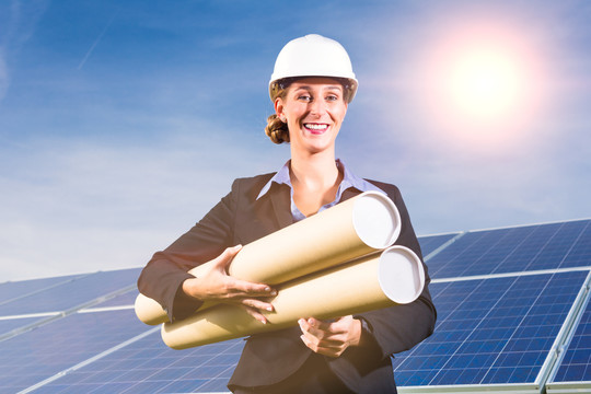 光伏系统采用太阳能电池板，通过太阳能生产可再生能源，一位建筑师站在前面