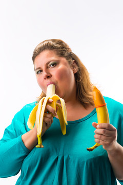 年轻女子手里拿着两个香蕉，安全套被一个套住，吃着另一个香蕉