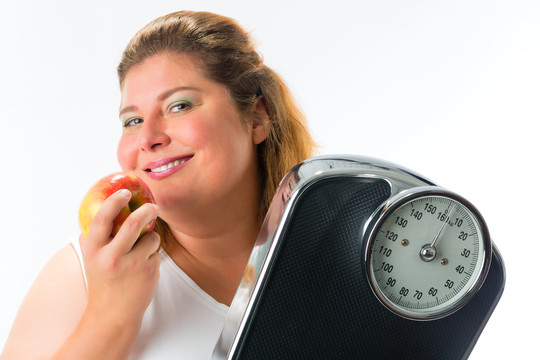 饮食和体重，手臂下有鳞片和苹果的肥胖年轻女子