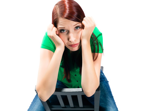 一个女人坐在工作室的椅子上，情绪低落或沮丧，甚至不知所措或无聊