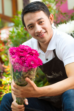 友好的亚洲花商或花店里拿着花束的卖家