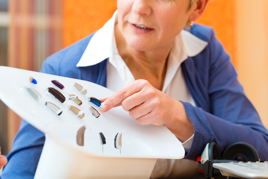 老年妇女或有听力问题的女性退休人员做听力测试，可能需要助听器，她正在挑选他们