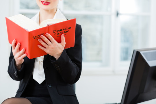 在办公室工作的年轻女律师在读一本典型的法律书