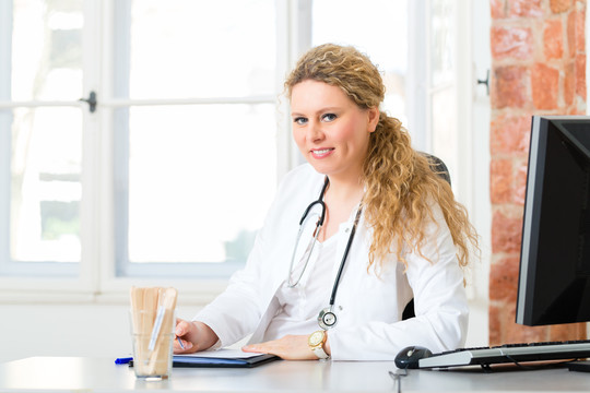 年轻的女医生坐在诊所窗户前的桌子旁写文件或档案