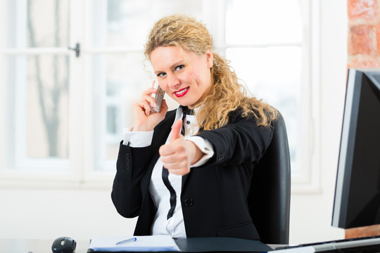 在办公室工作的年轻律师或秘书，她坐在办公桌上，打电话的是客户