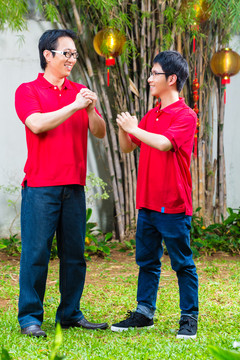 父亲和成年儿子穿着红衫庆祝中国新年