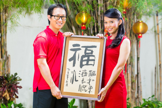 这对夫妇穿着红色衣服，用传统的礼物庆祝中国新年