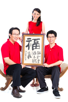 一家人穿着红色衣服，用传统书法庆祝中国新年