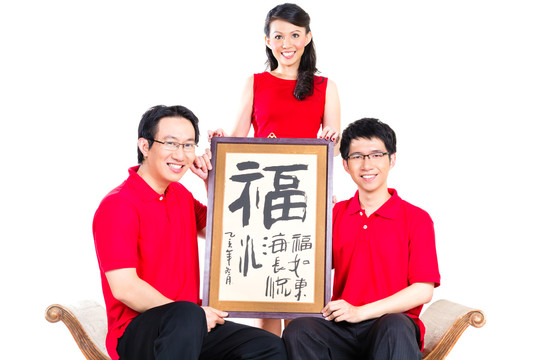 一家人穿着红色衣服，用传统书法庆祝中国新年