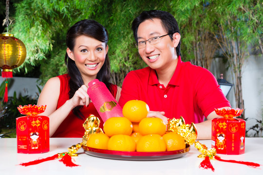 这对夫妇穿着红衫，用传统的礼物庆祝中国新年