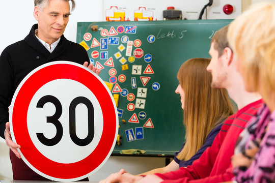 驾校-驾驶老师和学生驾驶者都有一个速度三十的路标，背景是交通标志