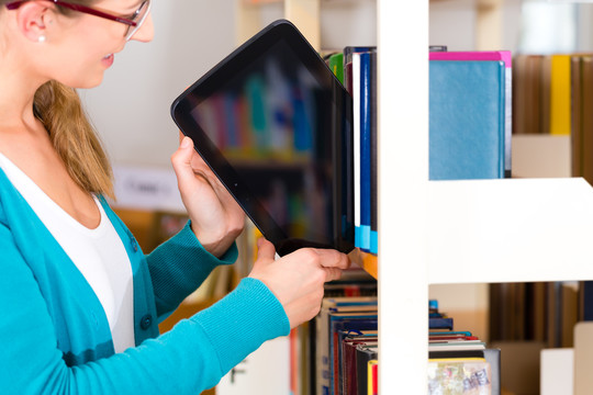 学生-从书架上拿出带电子书的平板电脑的年轻女性或女孩