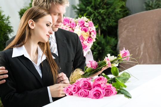 葬礼上的哀悼男女站在棺材或棺材前的粉红玫瑰