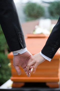 宗教，死亡和悲哀-在葬礼上的一对夫妇手牵手安慰对方的损失