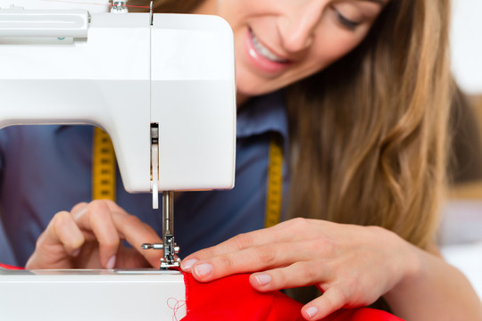 自由职业者-时装设计师或裁缝在设计或草案工作，她用缝纫机缝纫