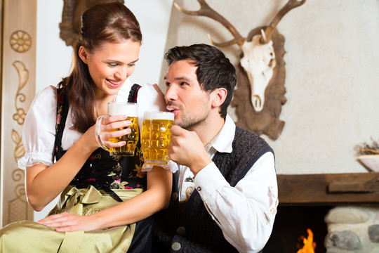 一对夫妇在传统的带壁炉的山间小屋里喝啤酒